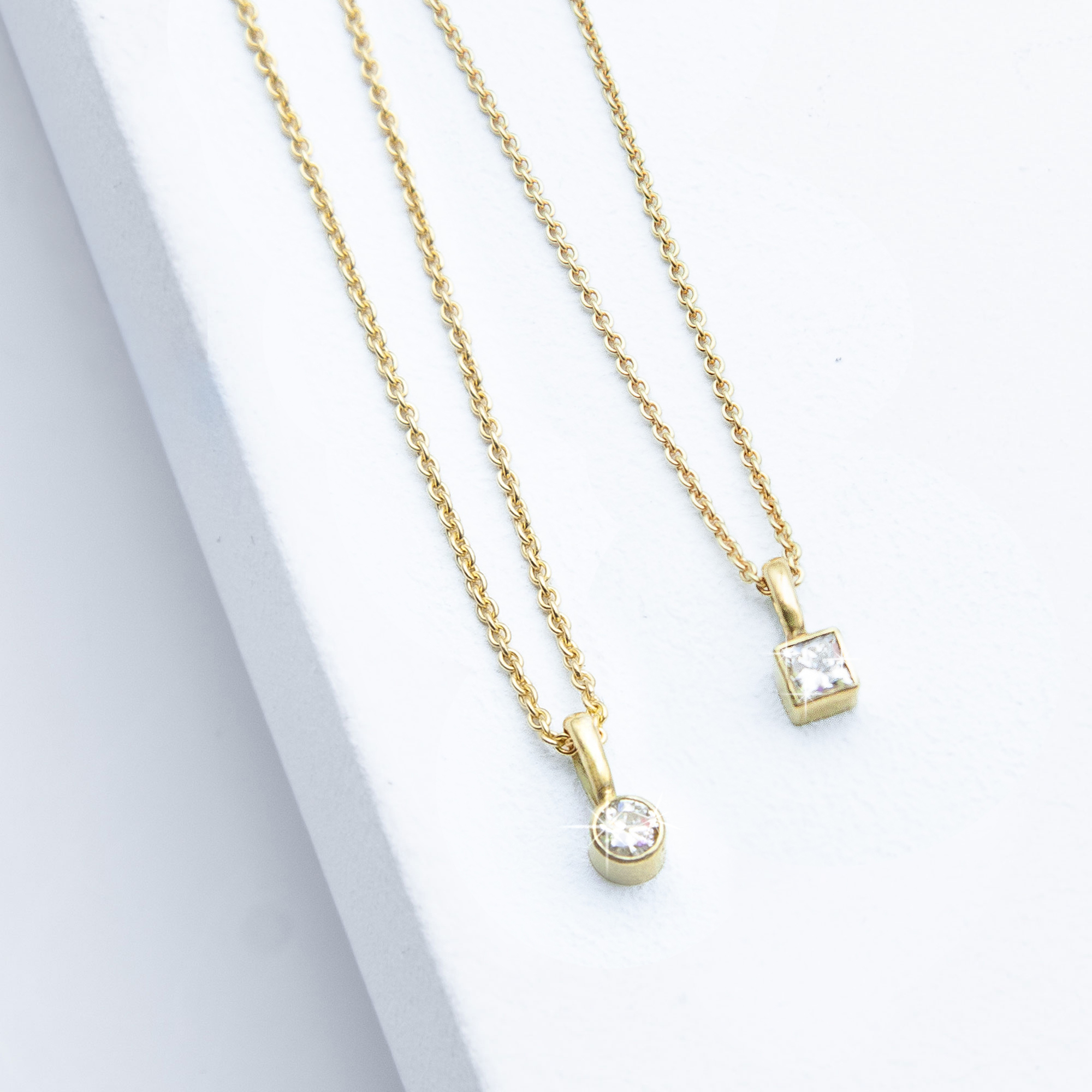Detailfoto der Sparkle Kollektion von Studio 4L – Diamantketten aus 585er Gelbgold mit 0,1 ct runden und 0,19 ct carré Labordiamanten in Zargenfassung, 45 cm Ankerkette, 1,1 mm Stärke.